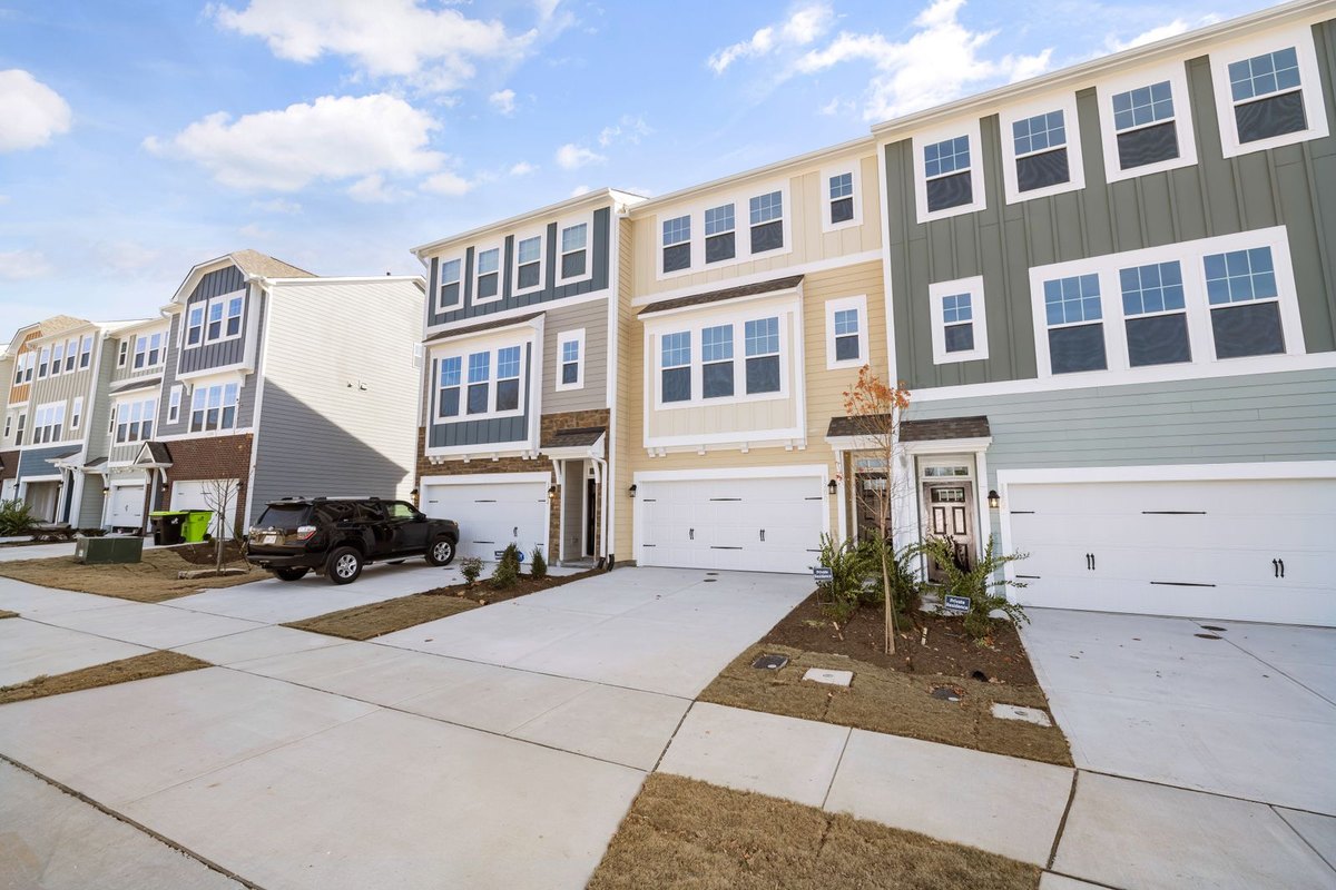 Row of new two-story townhomes with attached garages and fresh landscaping on a sunny day