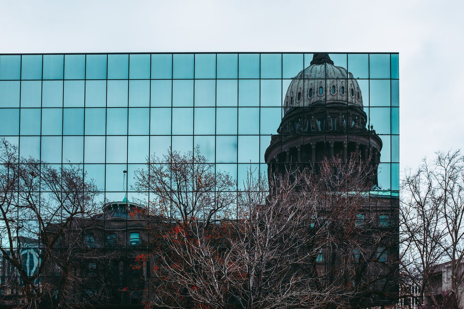 A capitol dome seen behind a glass office building