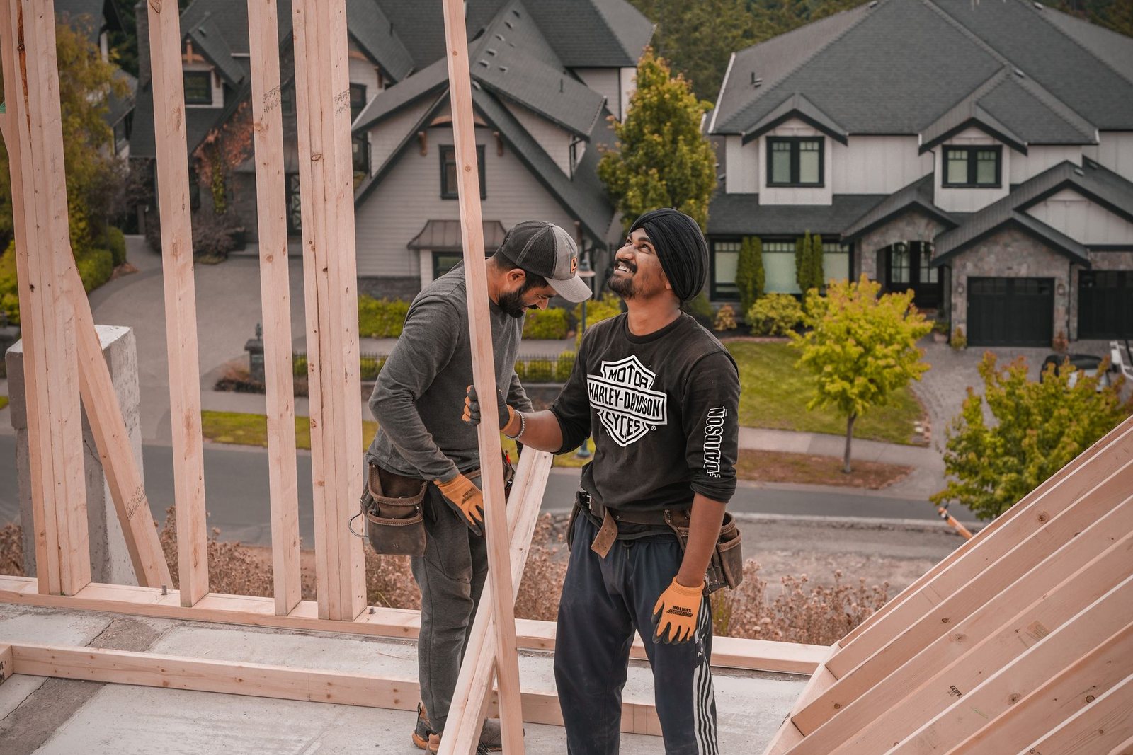 Two construction workers talking inside the wood framing of a house under construction