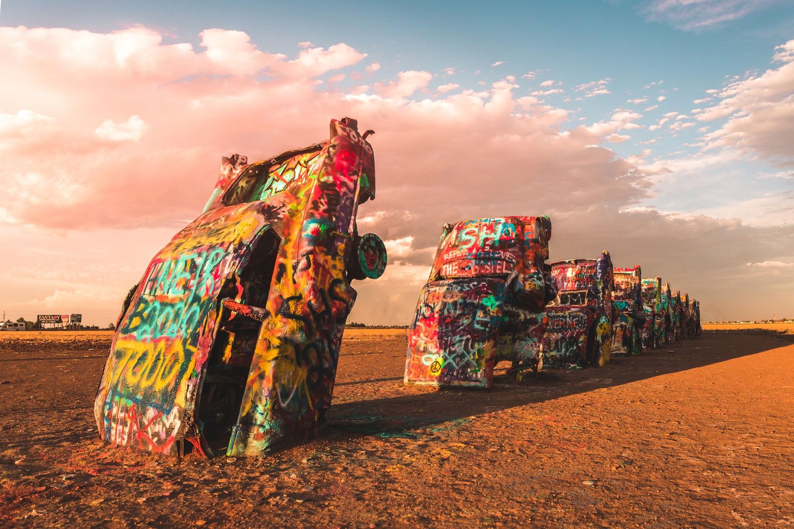 Spray-painted cars buried nose down at Cadillac Ranch at sunset