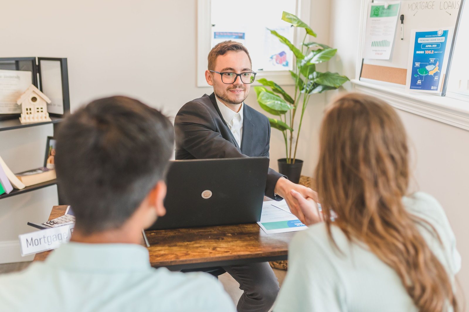 Couple meeting with a loan advisor at a desk with a laptop