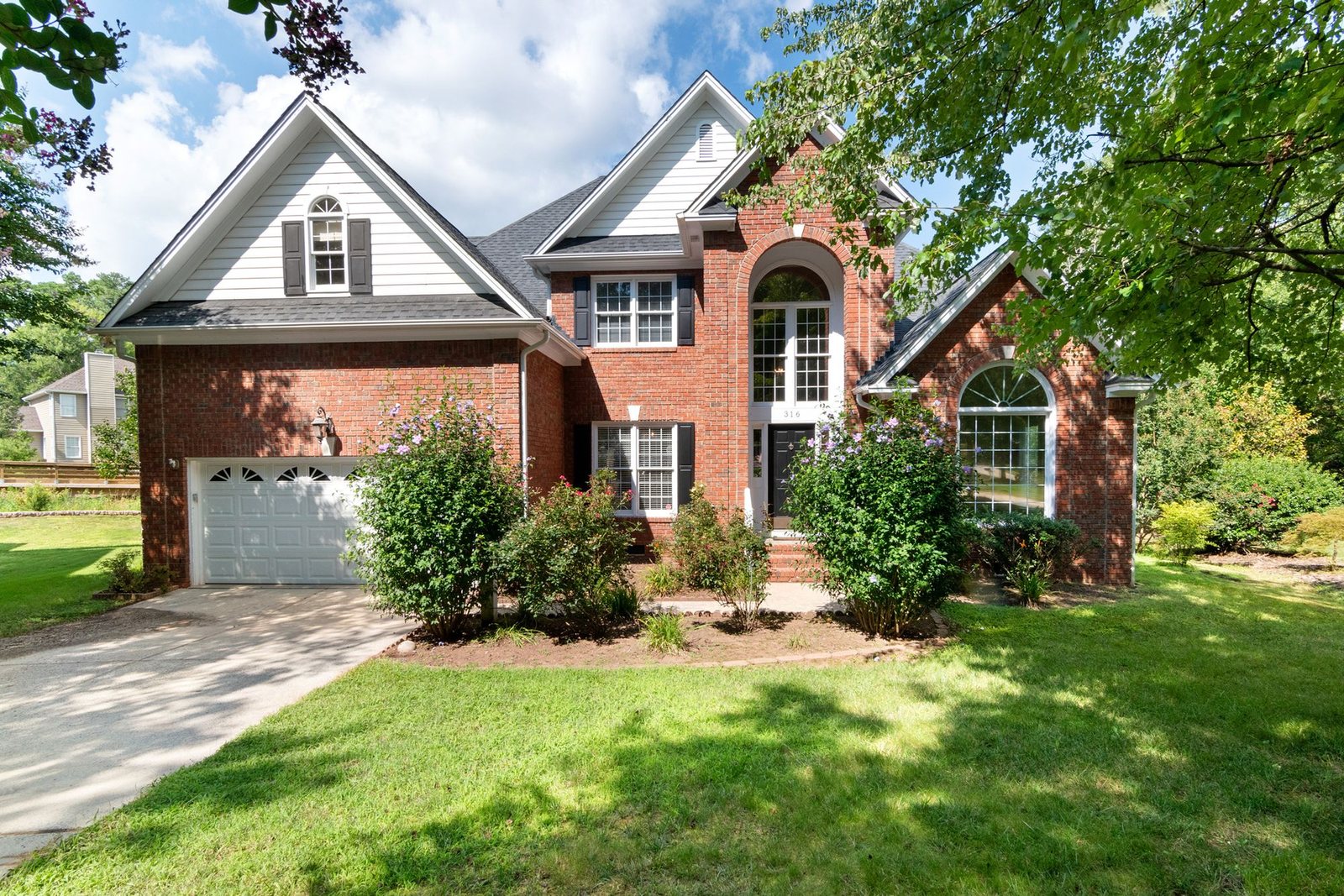 Brick suburban house with a front lawn and trees
