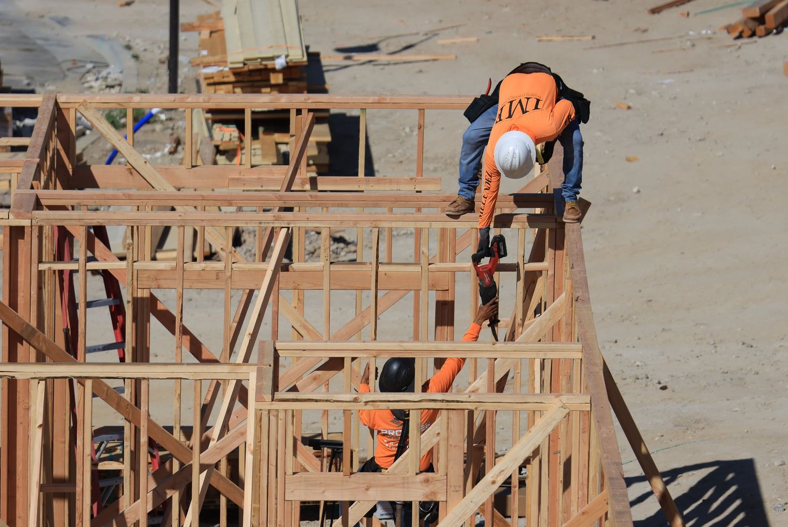 Construction crew framing the wood walls of a new single-family home on a sunny job site