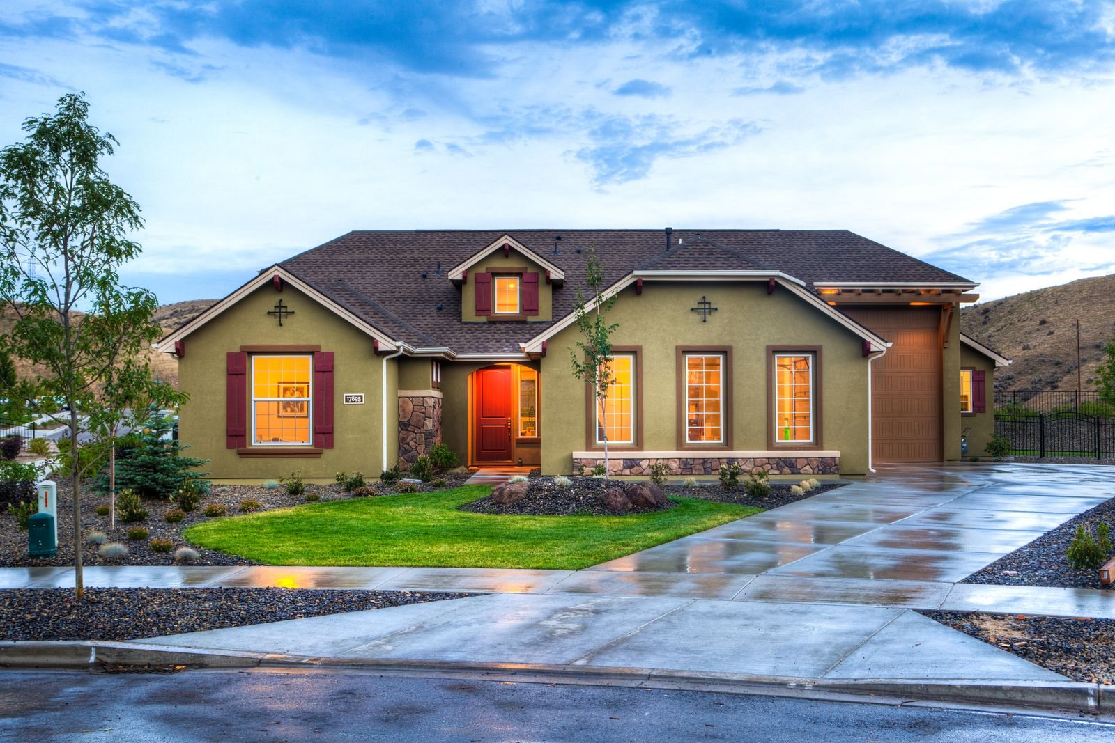 Single-family home with a porch and landscaped yard at dusk
