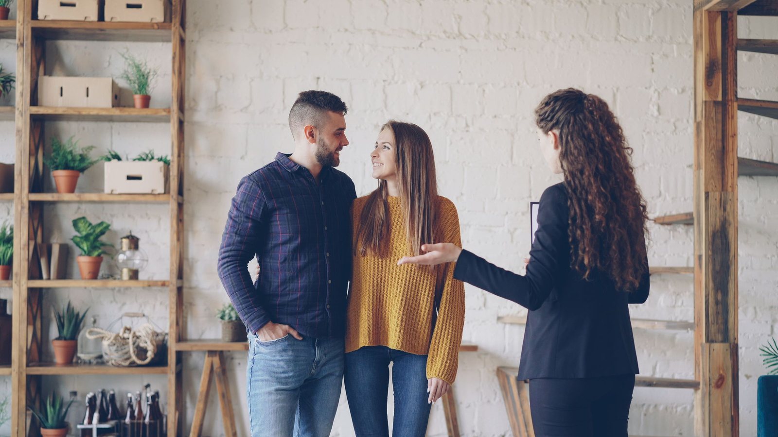 Couple talking with a real estate agent inside a home