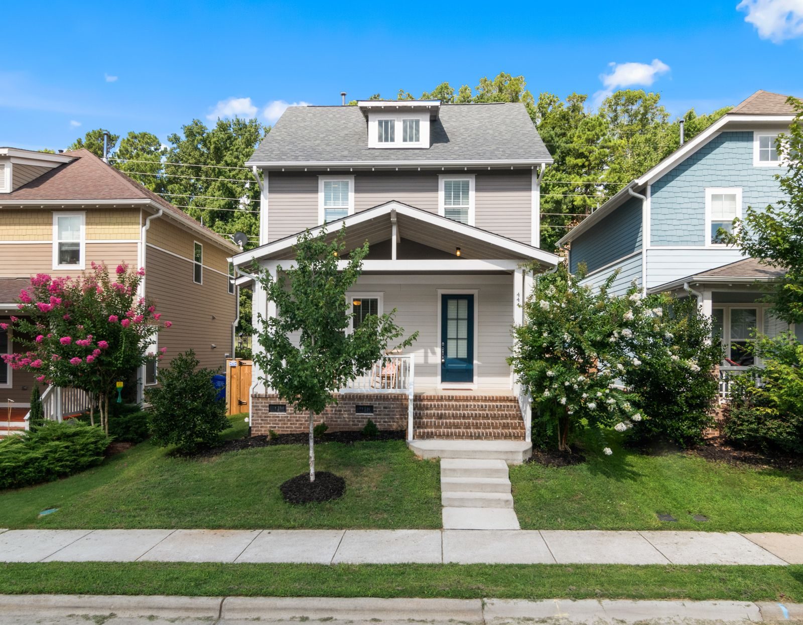 Two-story home with a covered front porch, white trim, and a green lawn