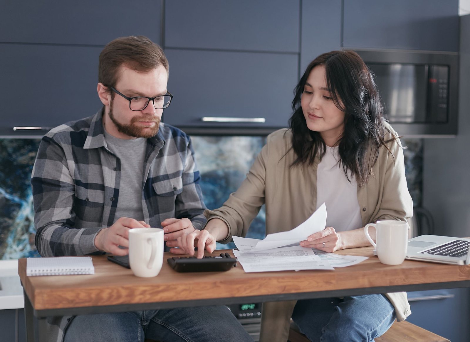 Couple at a kitchen table reviewing paperwork together
