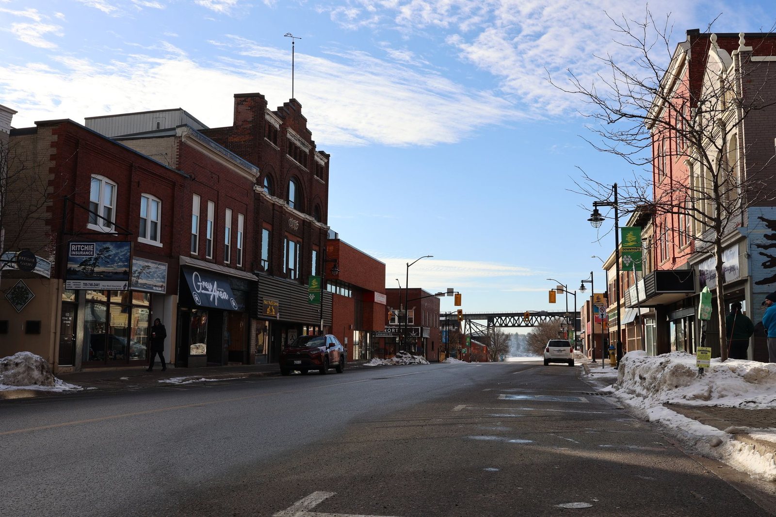 Small town street with brick storefronts and snow along the sidewalks