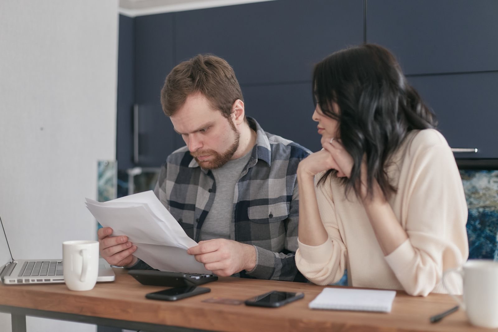 Couple reviewing loan paperwork at a kitchen table with coffee cups