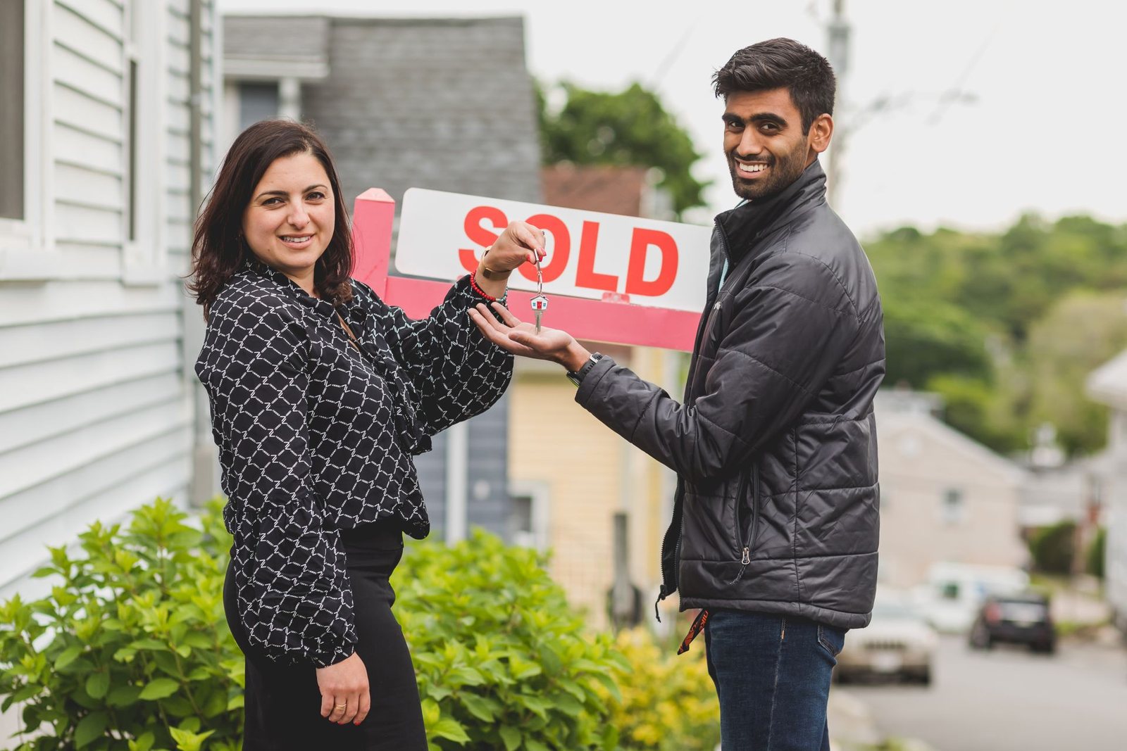 Agent handing keys to a new homeowner outdoors