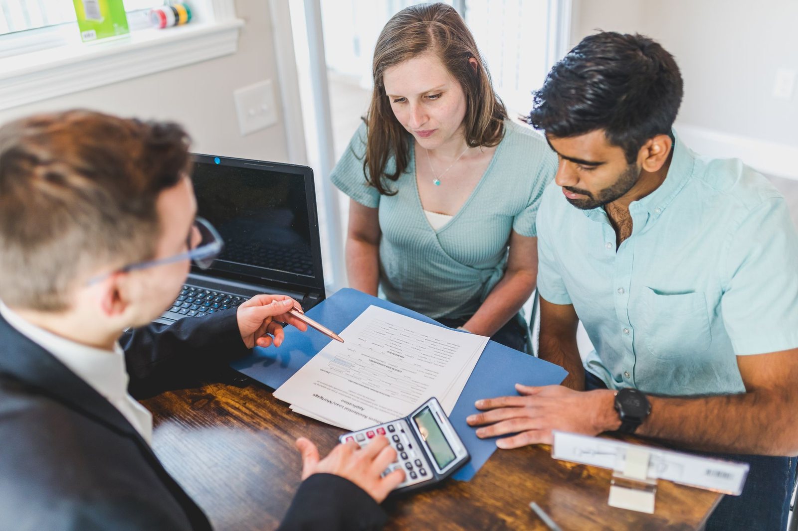Couple reviewing loan numbers with a mortgage advisor at a desk