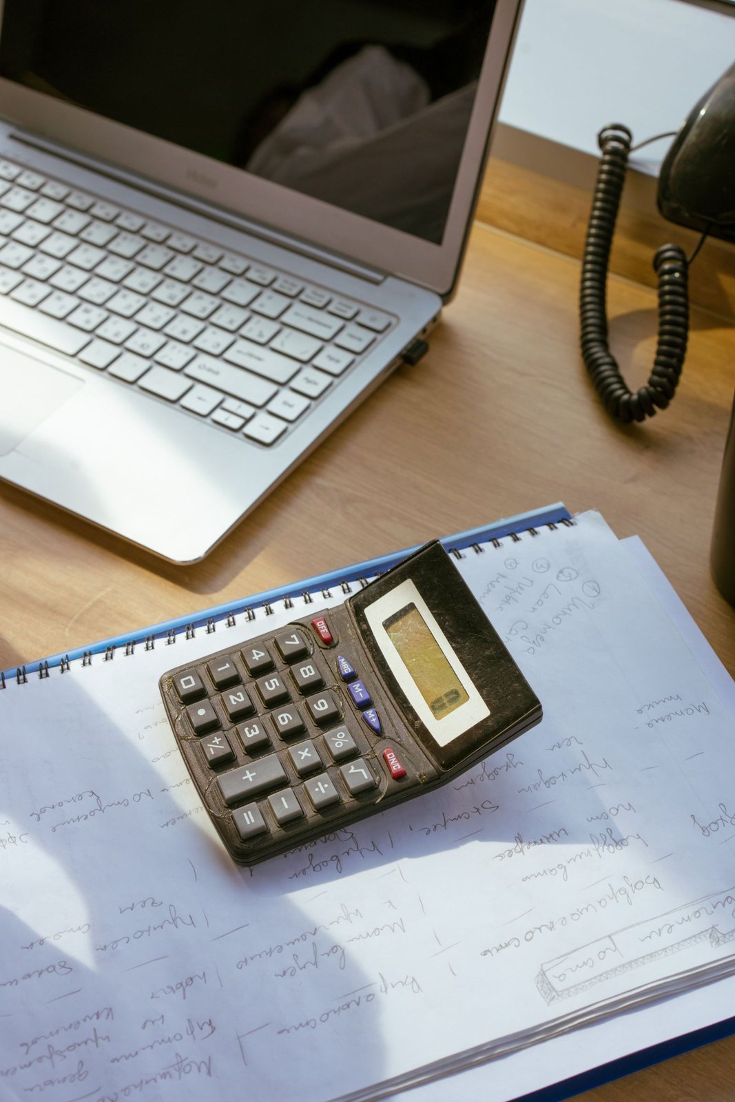 Calculator resting on a notebook next to an open laptop