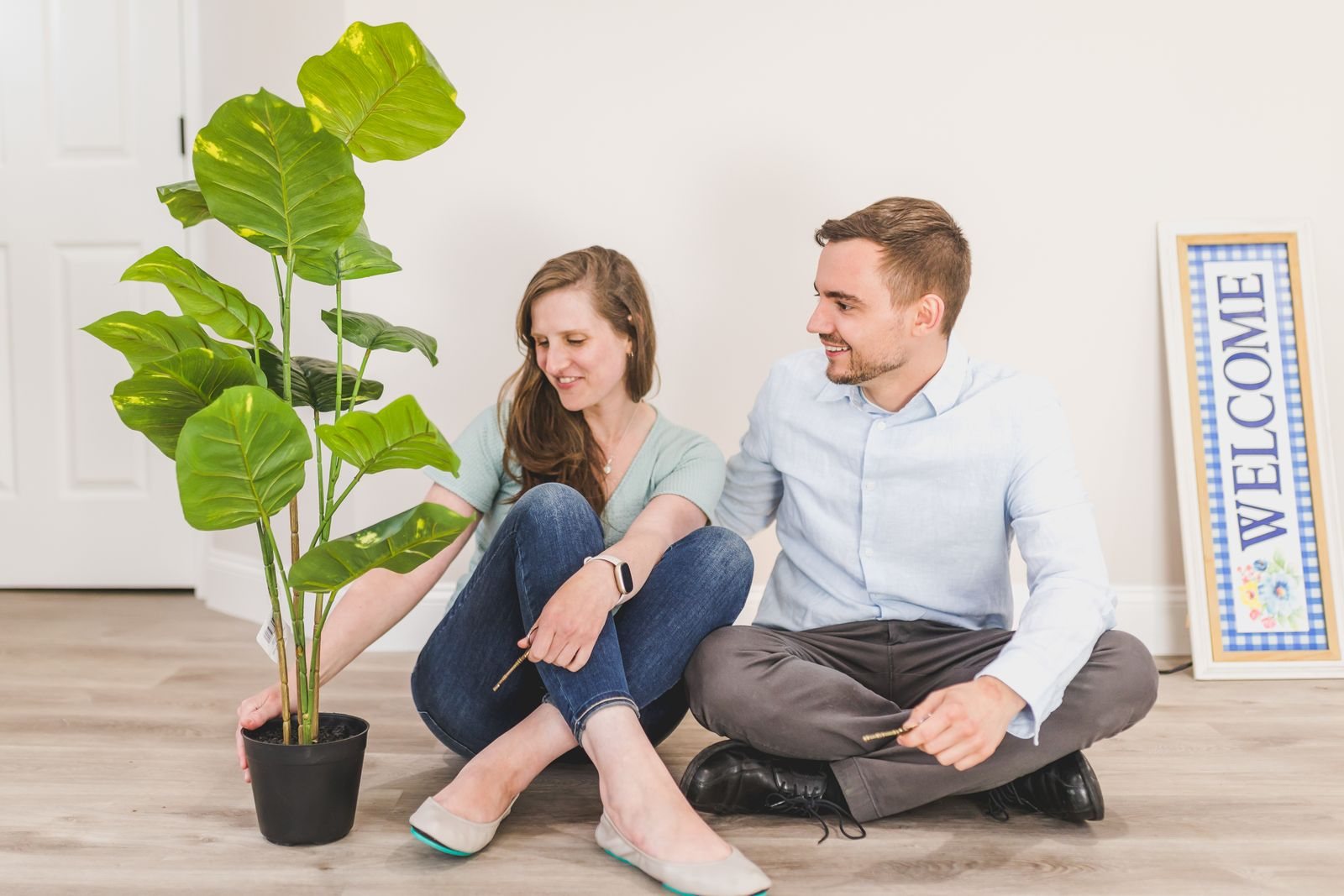 Young couple sitting on the floor of their new home next to a potted plant