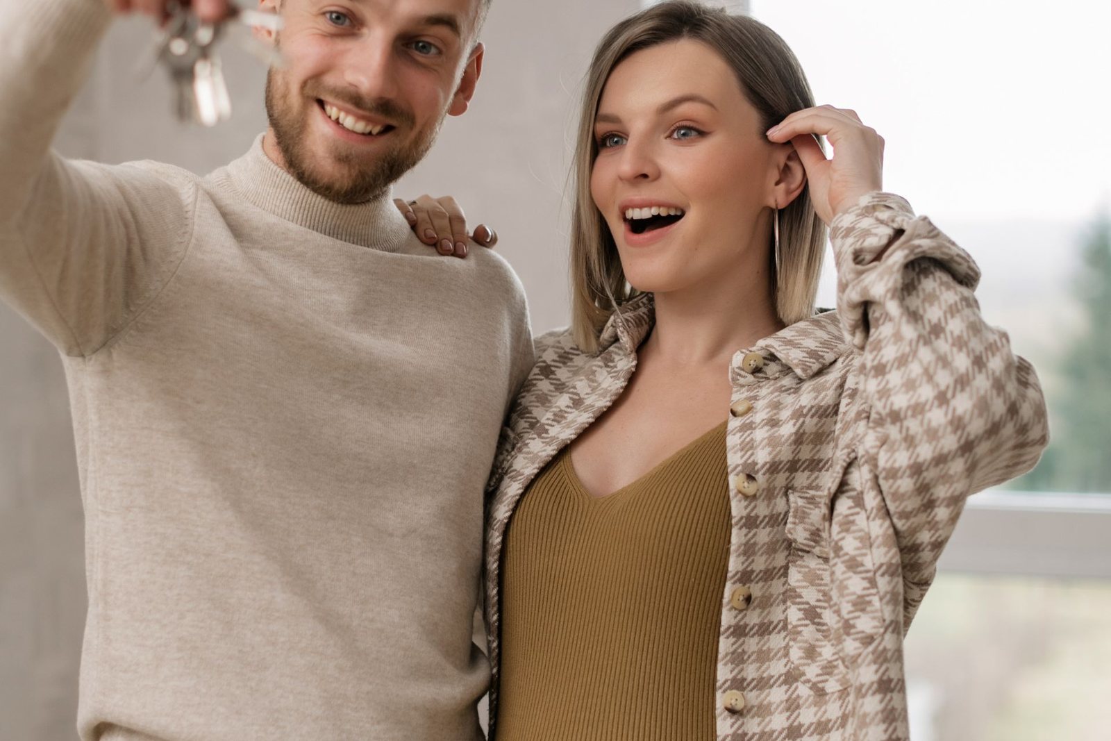 Smiling couple holding house keys after purchasing a home
