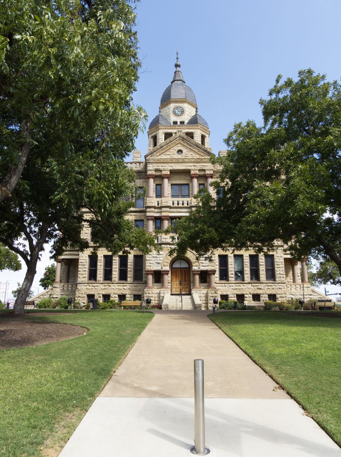 Historic Denton County courthouse with a walkway and trees in front