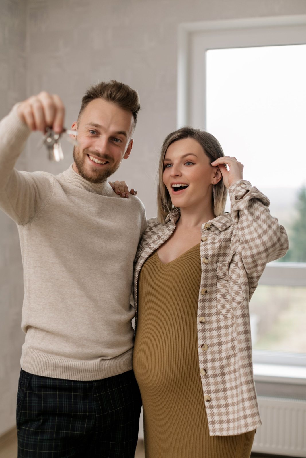 Happy couple holding up house keys inside their new home